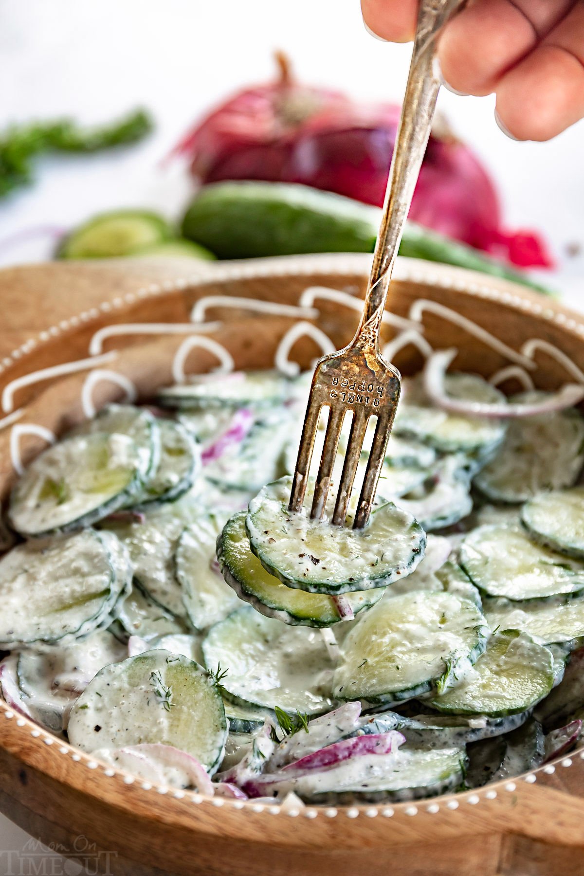 cucumber salad in large bowl with fork with two slices of cucumber on it