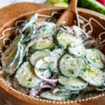 cucumber salad in wood bowl with wood spoon ready to serve.