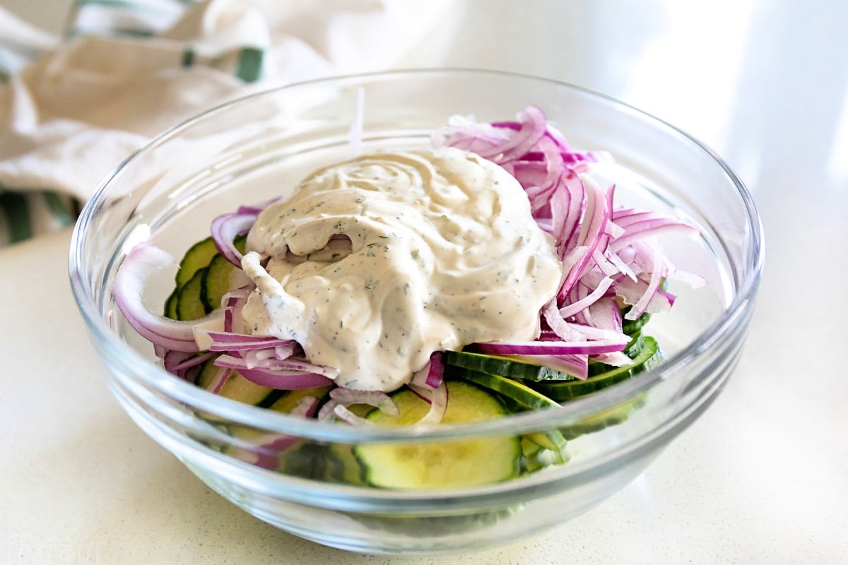 cucumber salad ingredients in a bowl with dressing on top