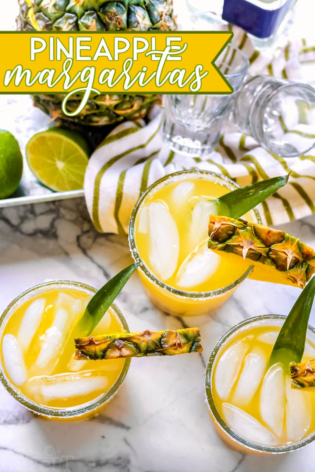 pineapple margaritas on marble cutting board with pineapple in the background and text overlay