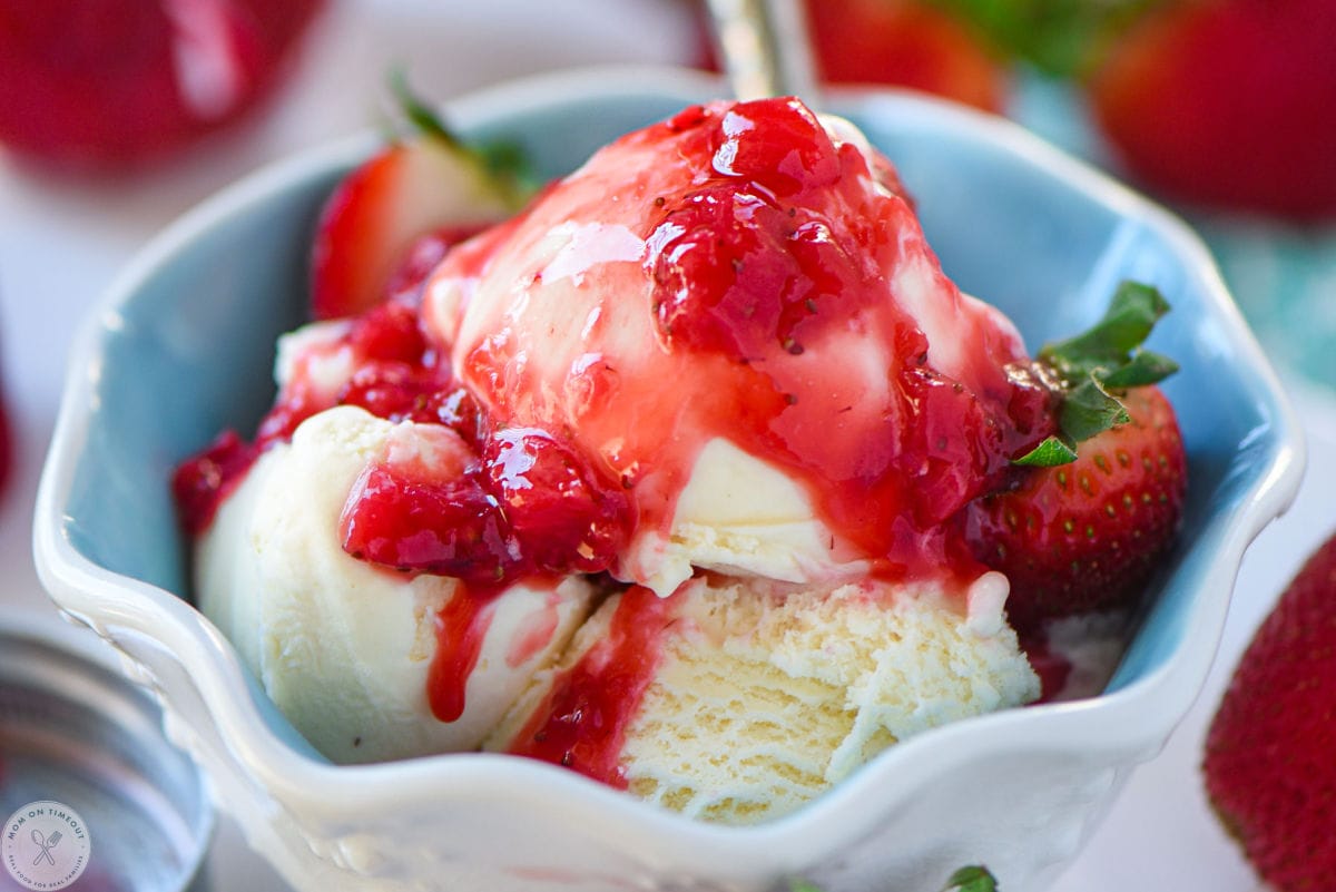Vanilla ice cream in dessert bowl topped with homemade strawberry fruit sauce.