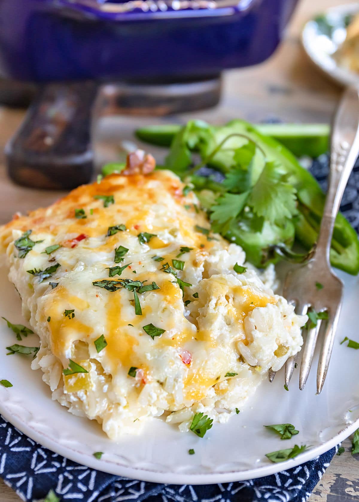 casserole served up on white plate with fork and topped with chopped cilantro