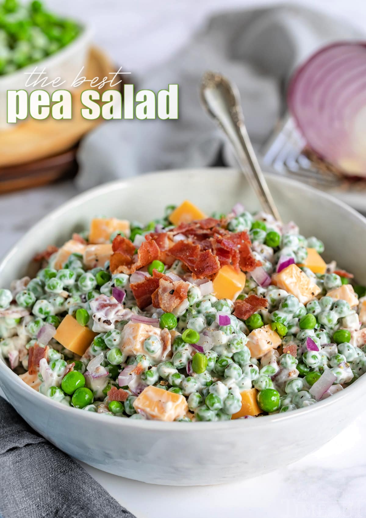 classic pea salad in a white bowl with spoon and title overlay on image