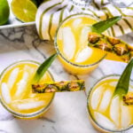 pineapple margaritas on marble cutting board with pineapple in the background square