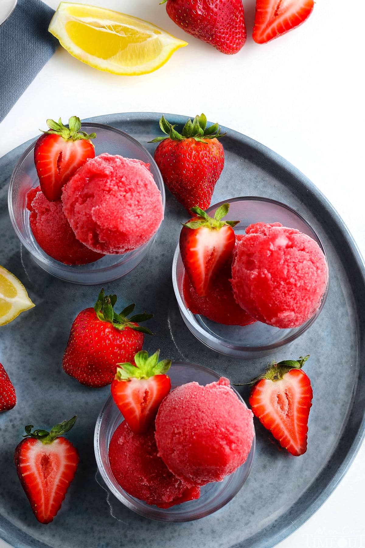 strawberry sorbet in three small glasses on gray plate with halved strawberries as garnish med res