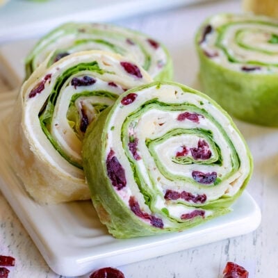 turkey pinwheels recipe with dried cranberries on small white cutting board squared
