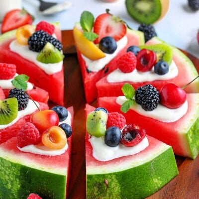 watermelon pizza recipe with a variety of fresh fruit on top cut into wedges on board square