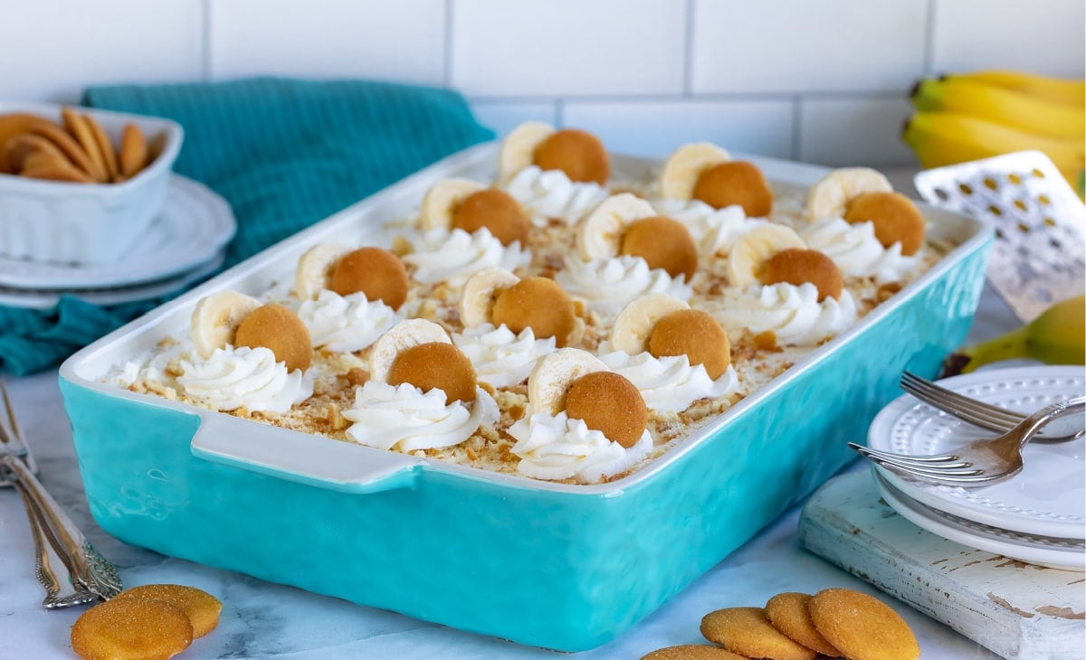 banana pudding in baking dish topped with dollops of whipped cream banana slices and nilla wafers