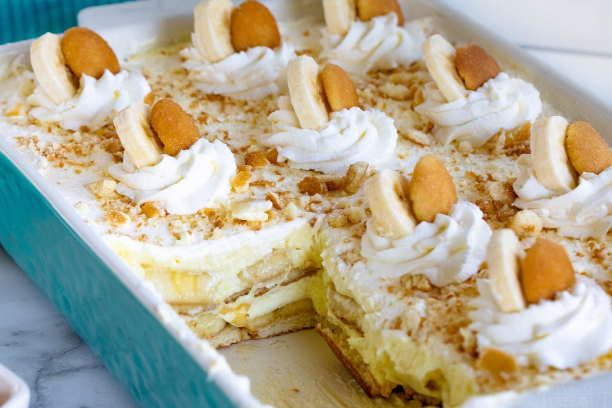 teal casserole dish with banana pudding recipe in it with a few servings removed