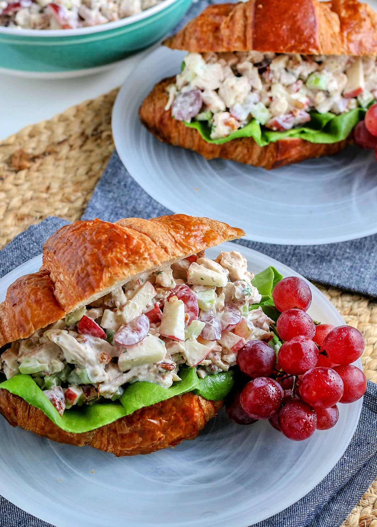 2 chicken salad sandwiches on white plates with blue napkins