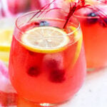 berry lemonade in a wine glass garnished with lemon slices square