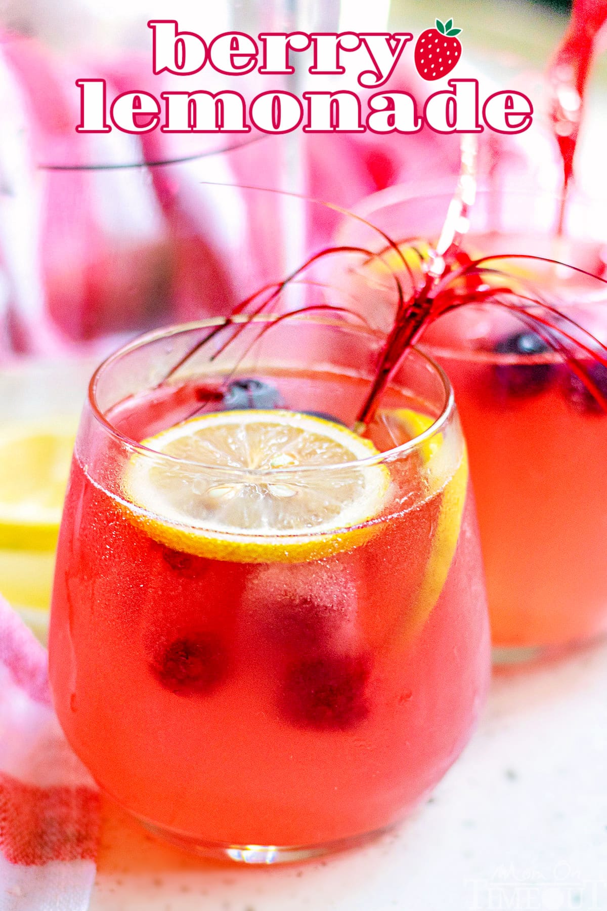 berry lemonade in a wine glass garnished with lemon slices with title overlay