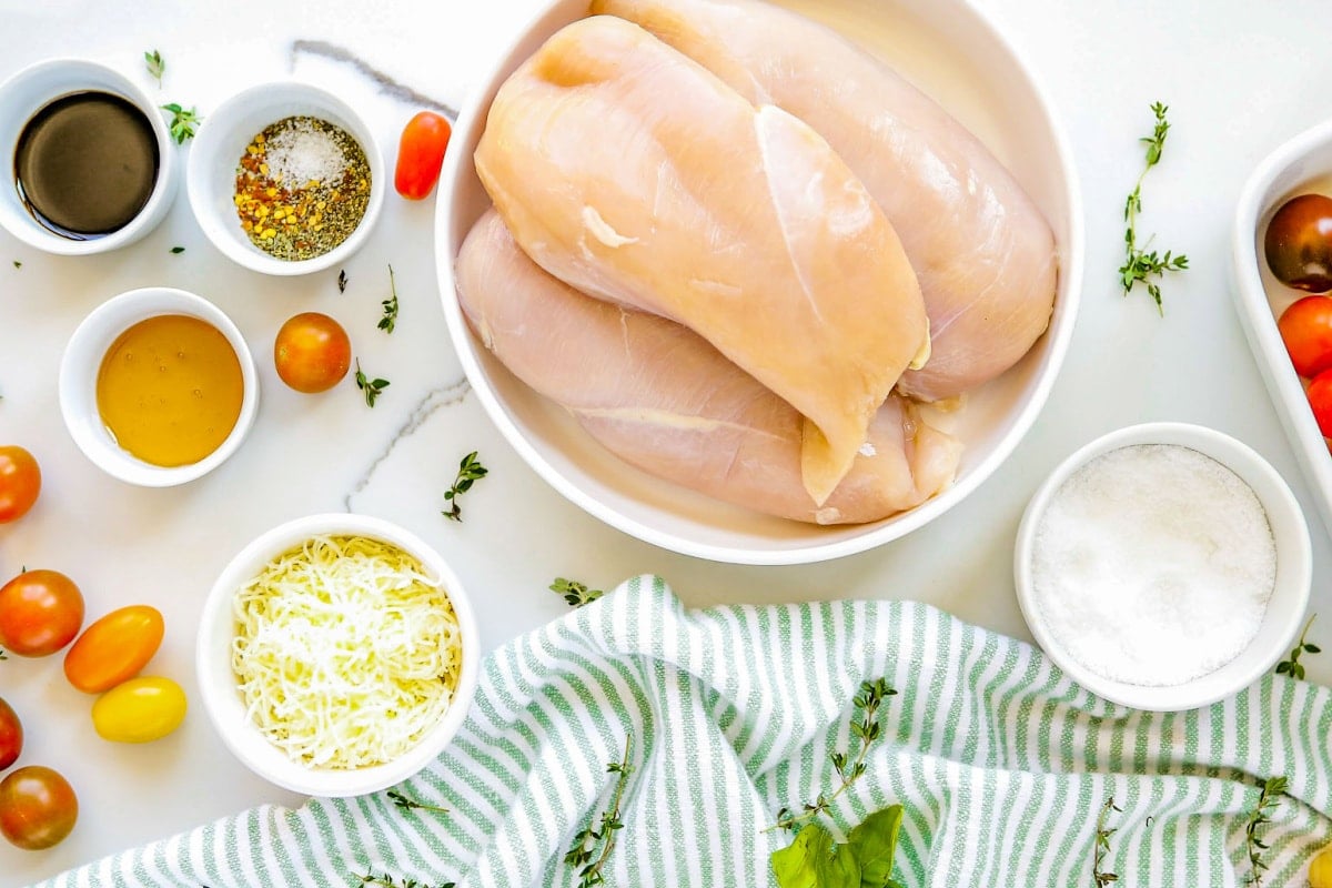 tomato basil baked chicken ingredients all layed out on white surface