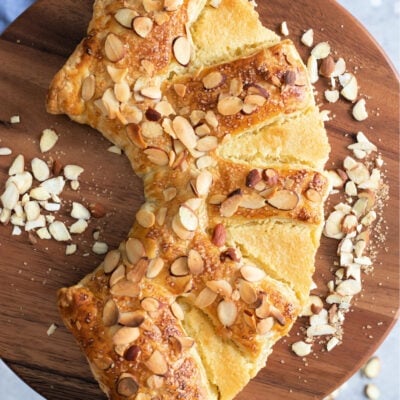 top down view of almond bear claw on cake pedestal with blue napkin underneath squared