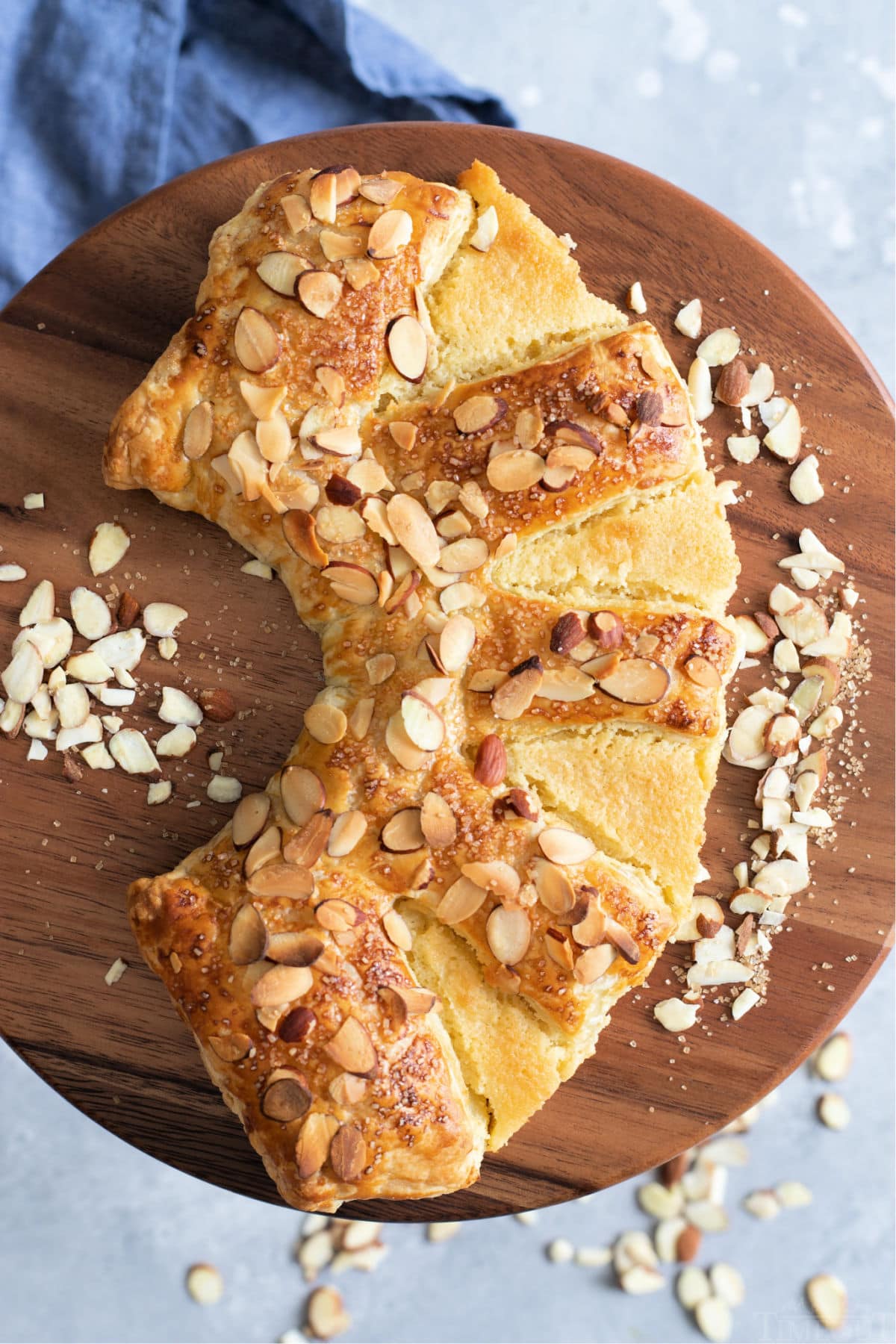 top down view of almond bear claw on cake pedestal with blue napkin underneath