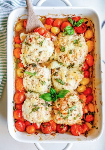 chicken and tomatoes on plate with side salad with casserole dish in background