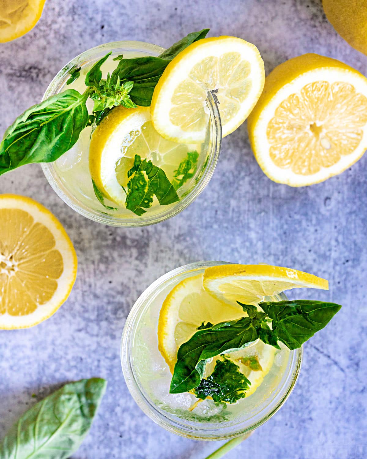 top down view of two glasses with basil lemon drop garnished with fresh basil and lemon slices