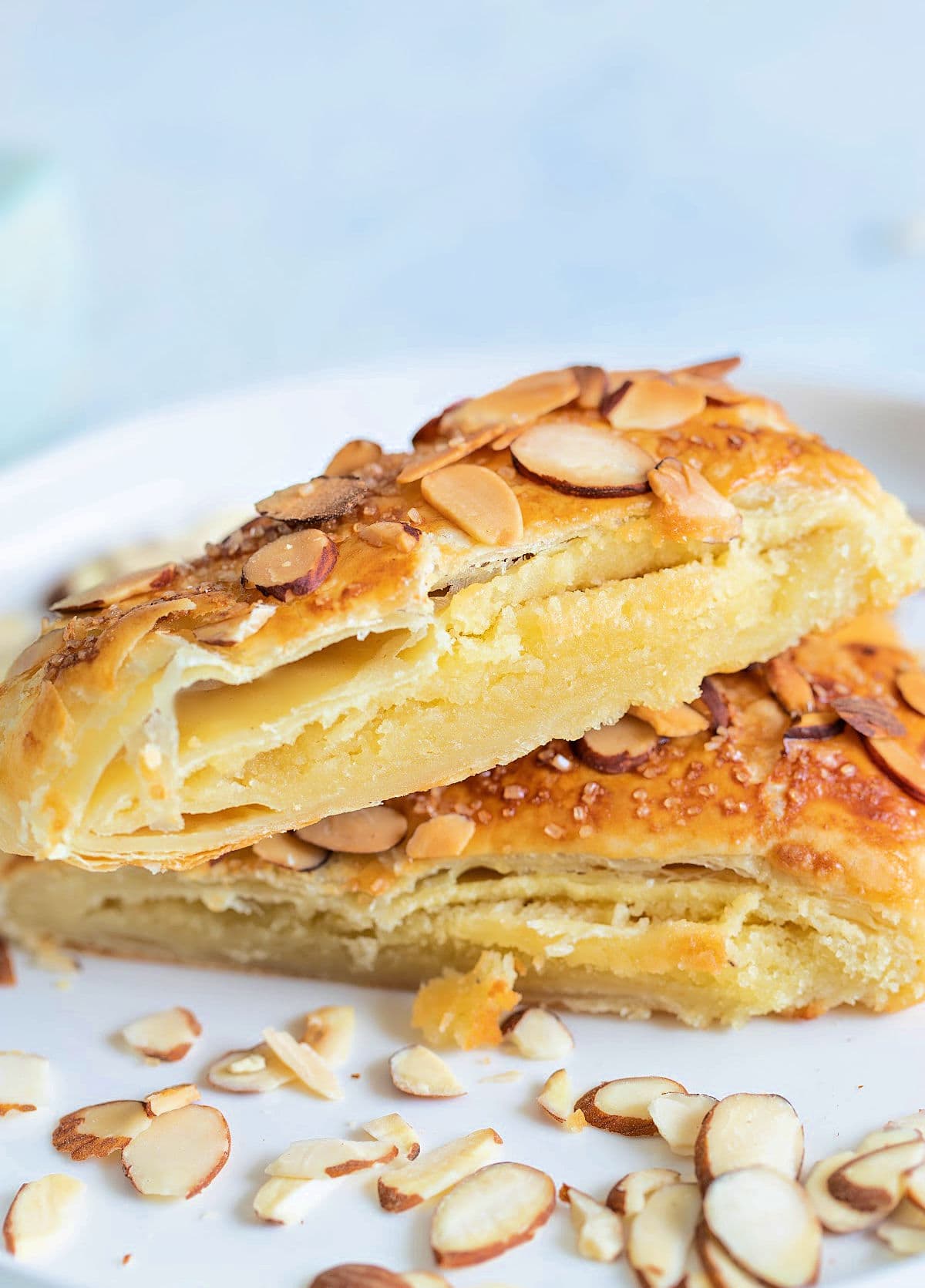 two pieces of Bear Claw pastry on white plate garnished with sliced almonds white background with almond bear claw