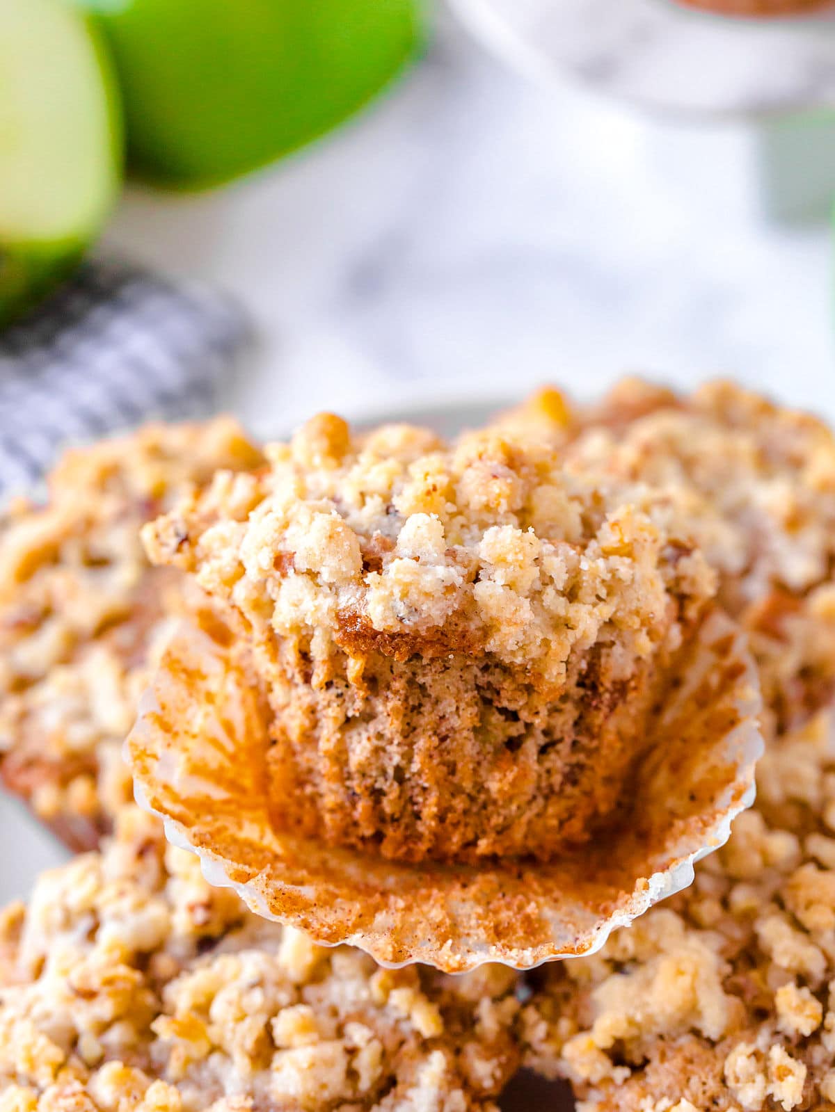 apple muffin unwrapped sitting on a plate of muffins