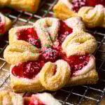 cheese danish with cherries baked and sprinkled with powdered sugar sitting on wire cooling rack square