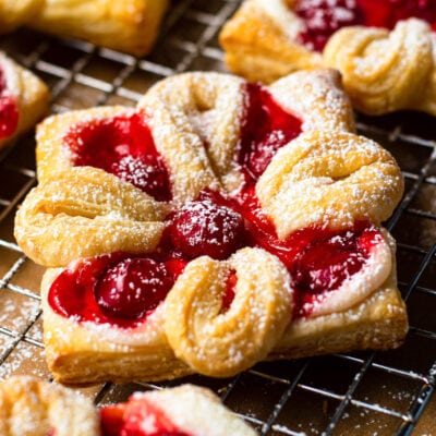 cheese danish with cherries baked and sprinkled with powdered sugar sitting on wire cooling rack square