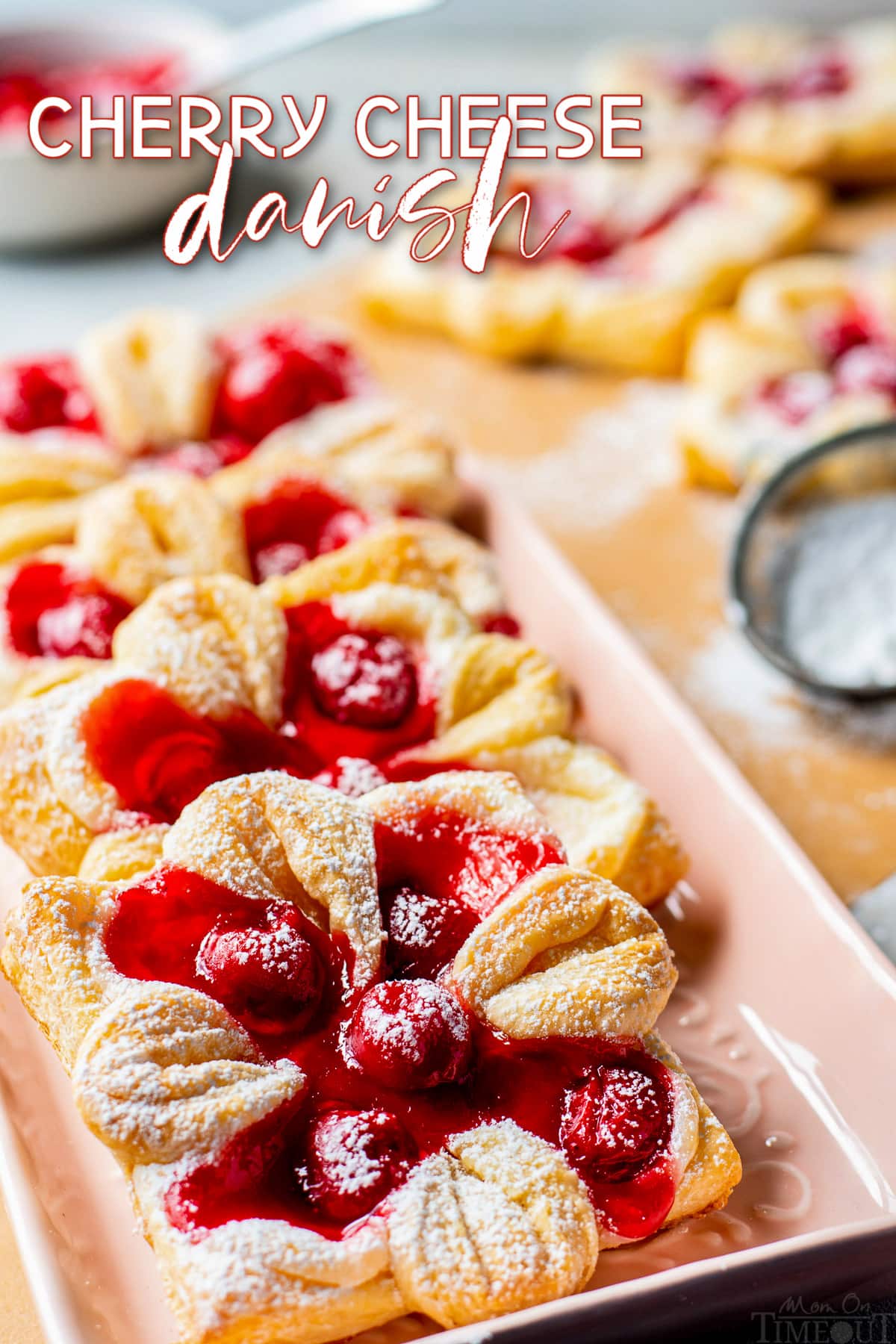 cherry cheese danishes on light pink tray dusted with powdered sugar and text overlay at the top