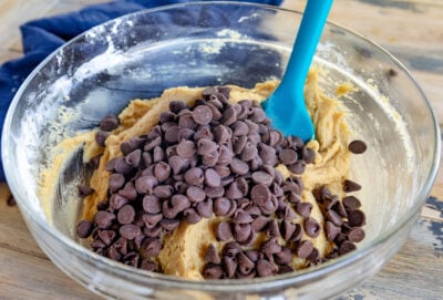 chocolate chips added to chocolate chip cookie dough in glass bowl