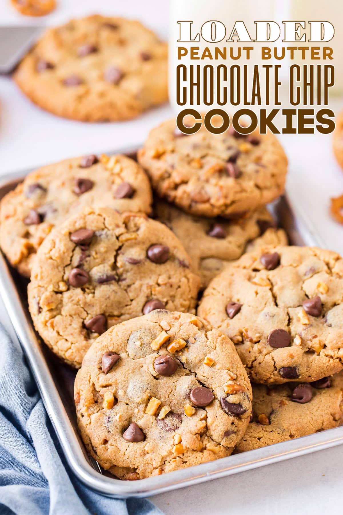 pile of loaded peanut butter chocolate chip cookies in eigth sheet pan with blue napkin front and text overlay at top