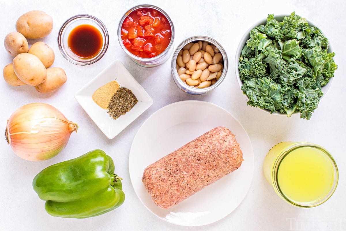 all of the ingredients for the sausage kale soup measured out into little bowls and plates sitting on white surface