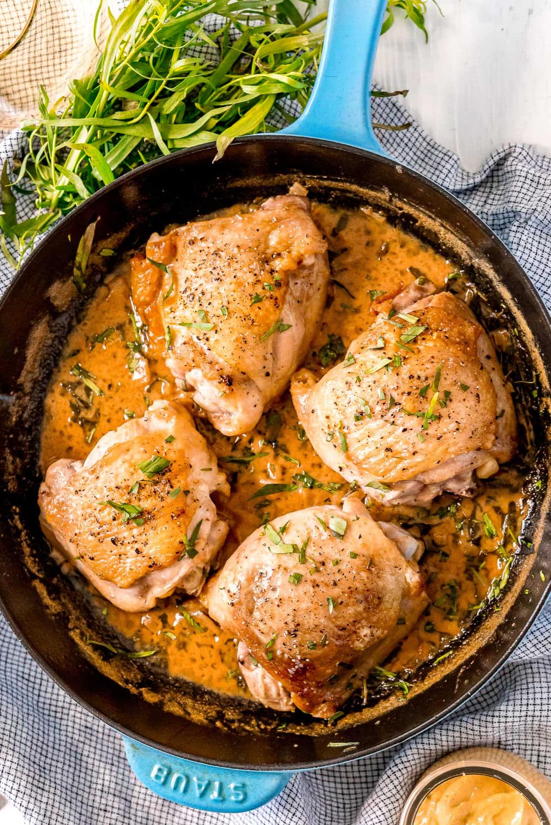 top down view of 4 chicken thighs in cast iron skillet with a creamy mustard sauce on top