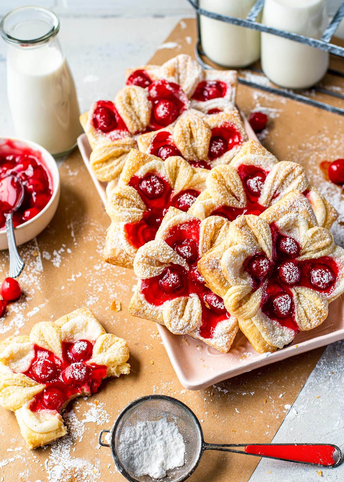 top down view of all of the cheese danishes with cherries on a tray and with powdered sugar