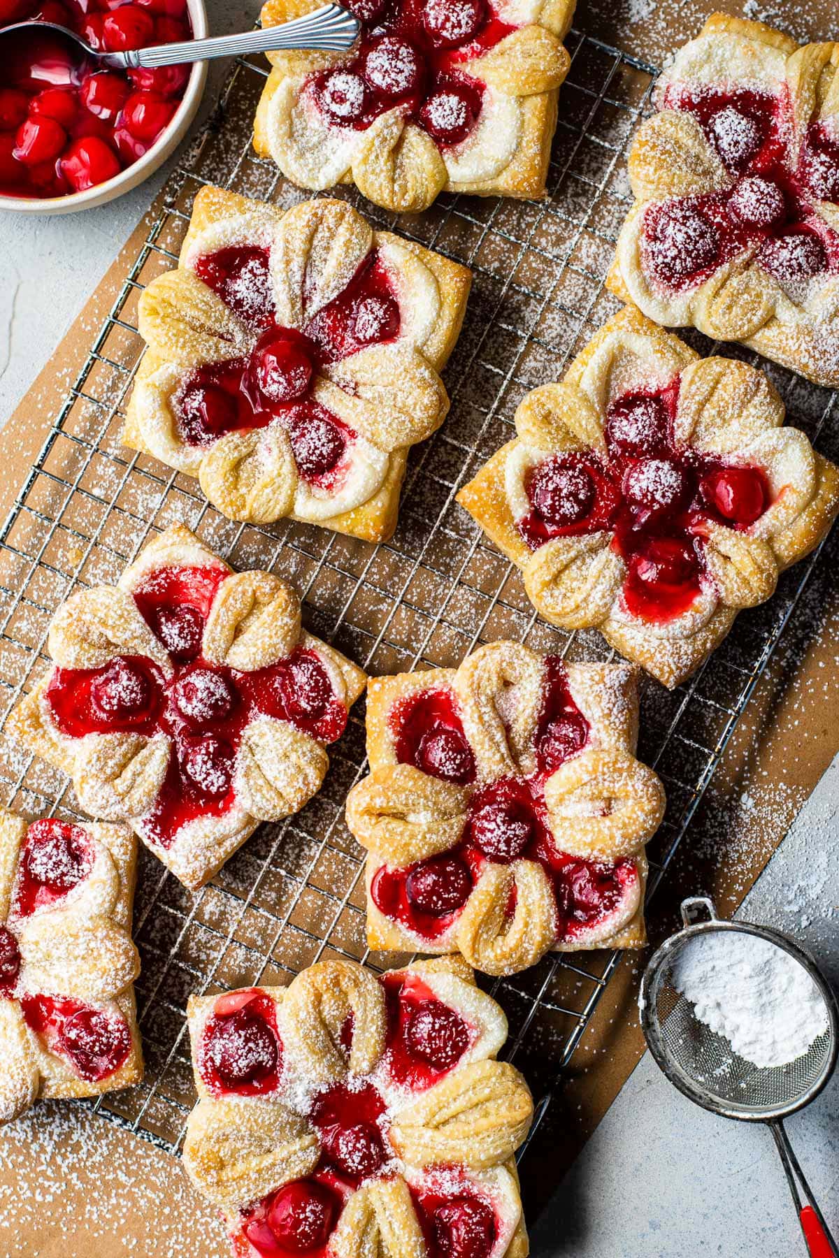 top down view of cherry danishes on brown parchment paper with powdered sugar sprinkled over the top