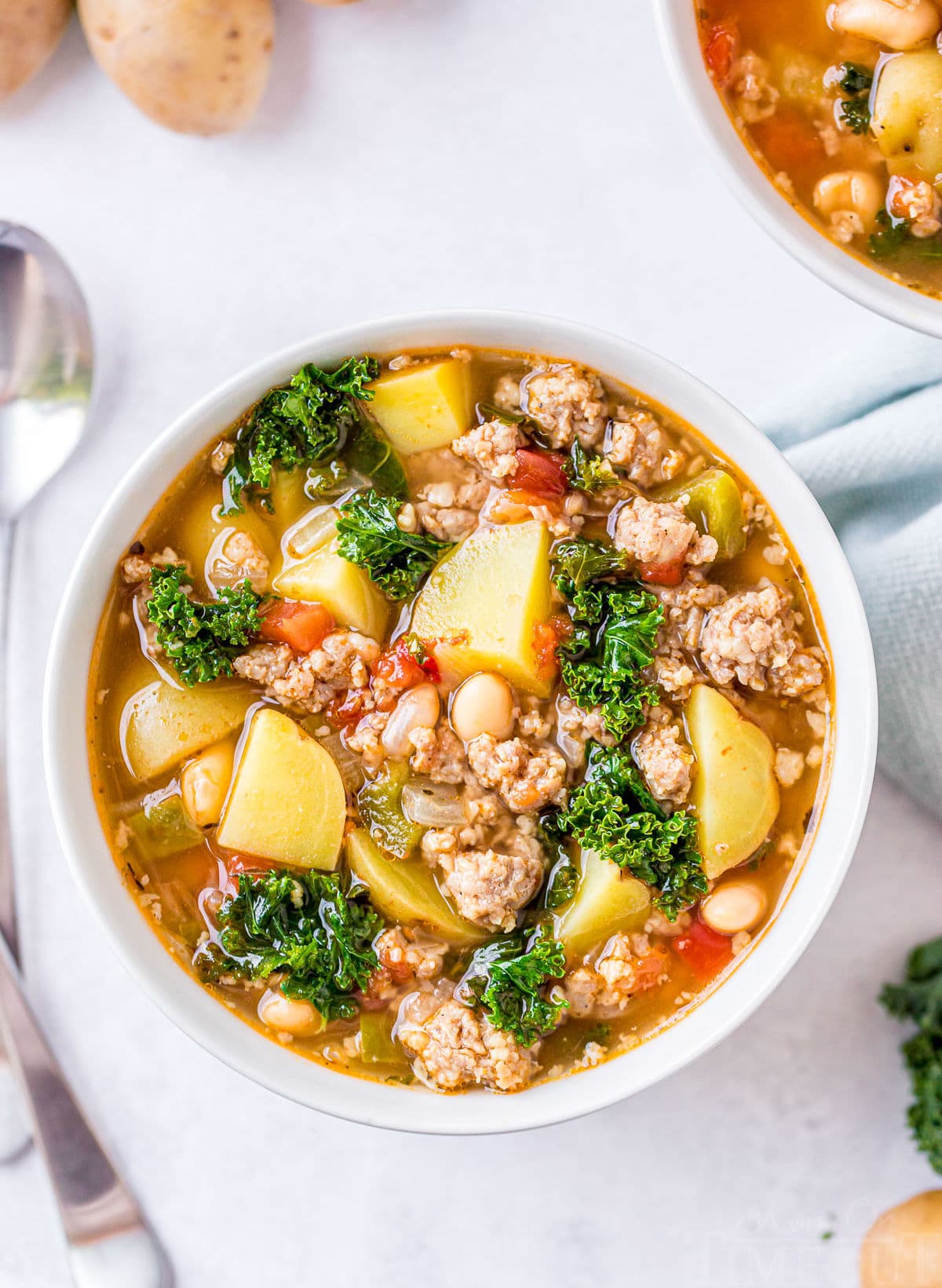 top down view of sausage potato soup with two spoons resting to the side