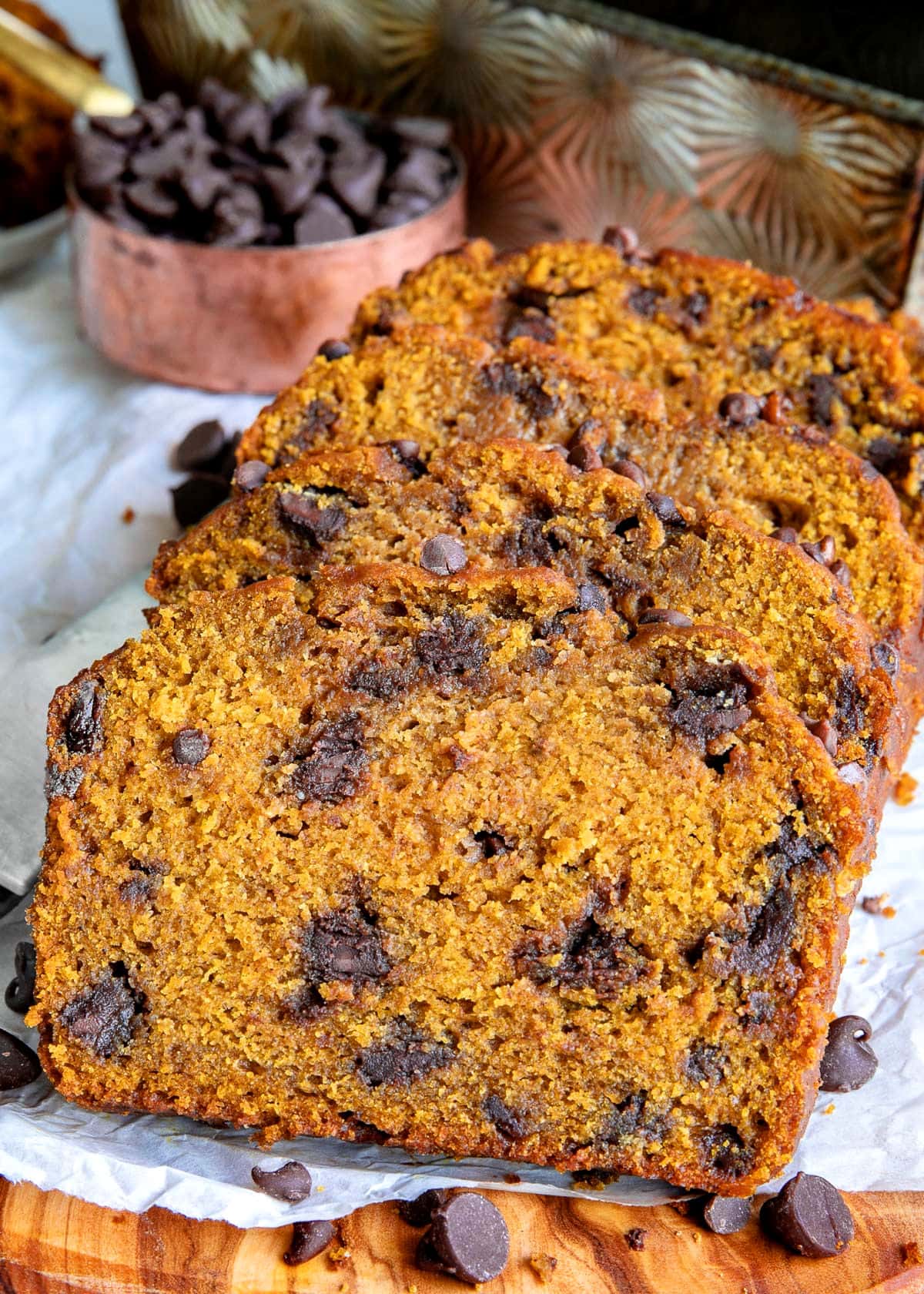 three slices of pumpkin chocolate chip bread laying on each either on a piece of parchment