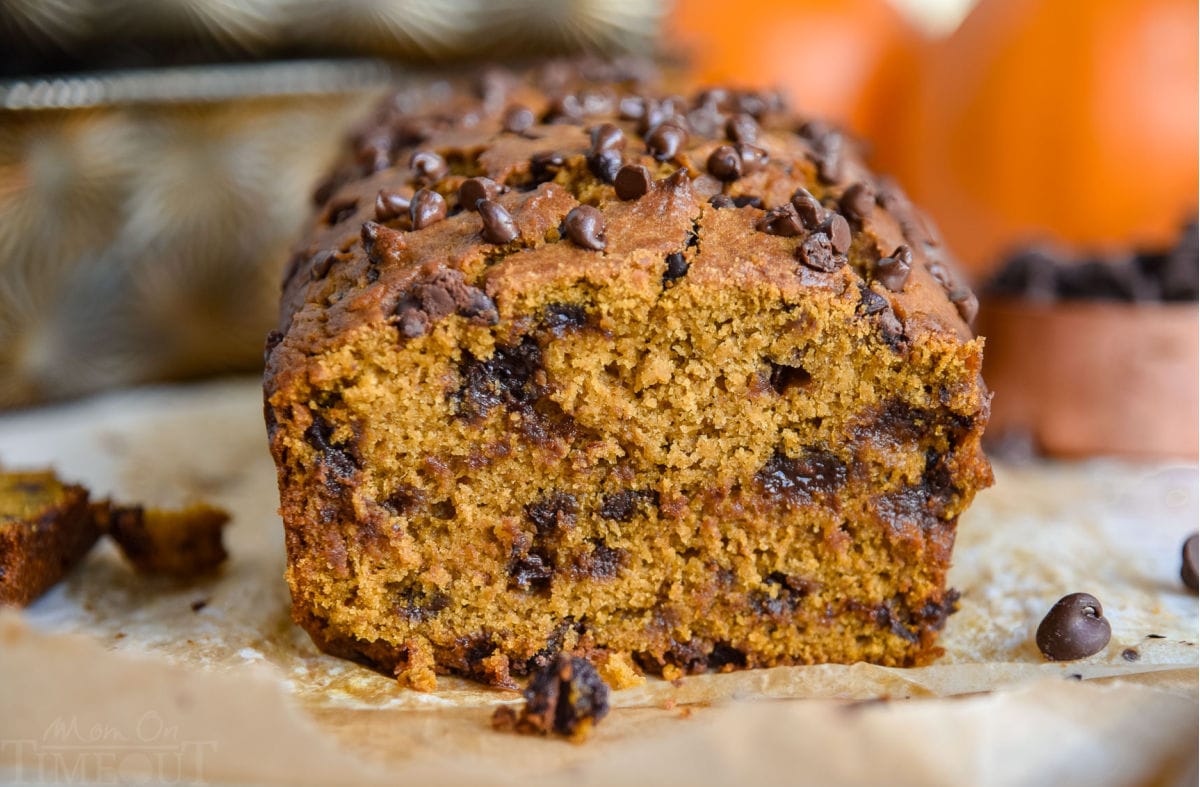 warm loaf of pumpkin bread with one slice removed sitting on parchment