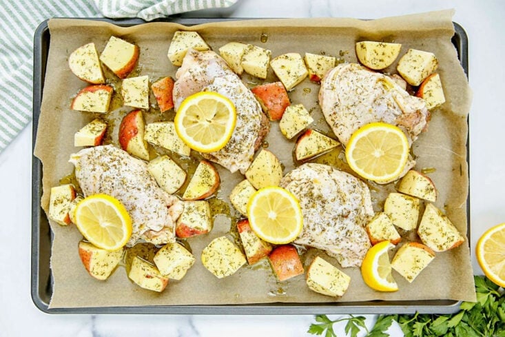 greek chicken and potatoes on sheet pan prepared to go in the oven to bake