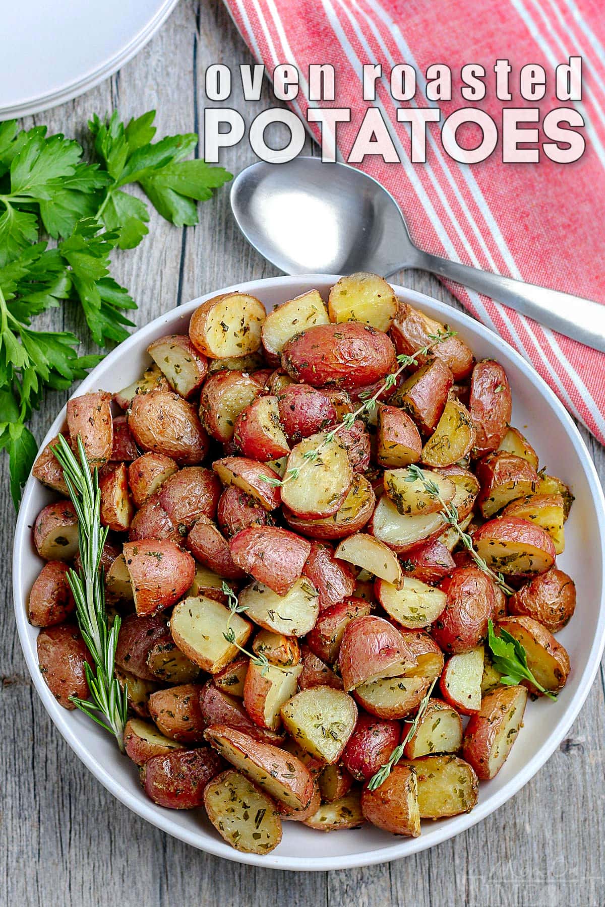 white plate with roasted potatoes garnished with fresh herbs and red towel in the upper right corner white text overlay