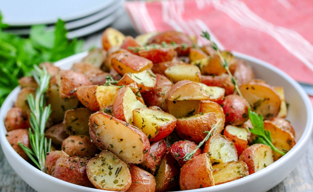 oven roasted potatoes in white bowl with fresh herbs on top wide shot