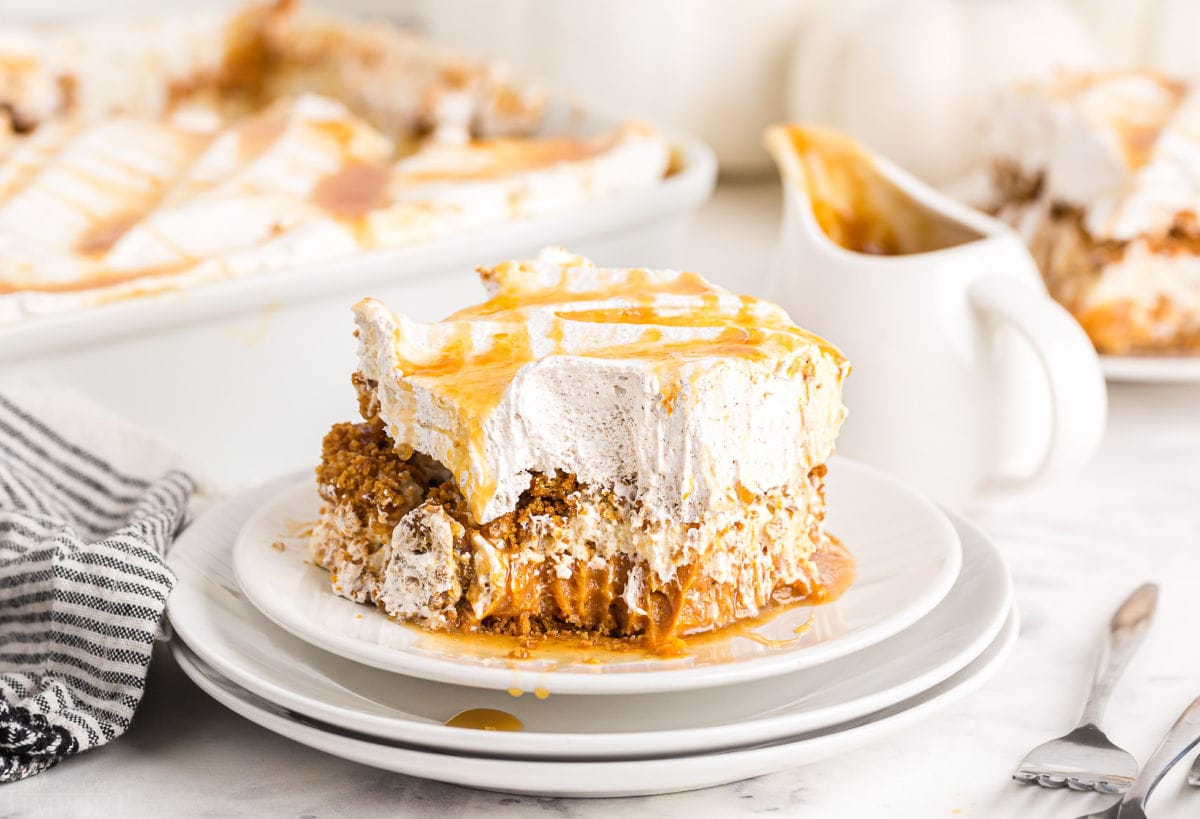 pumpkin dessert served on white plate with caramel sauce on top and baking dish in background