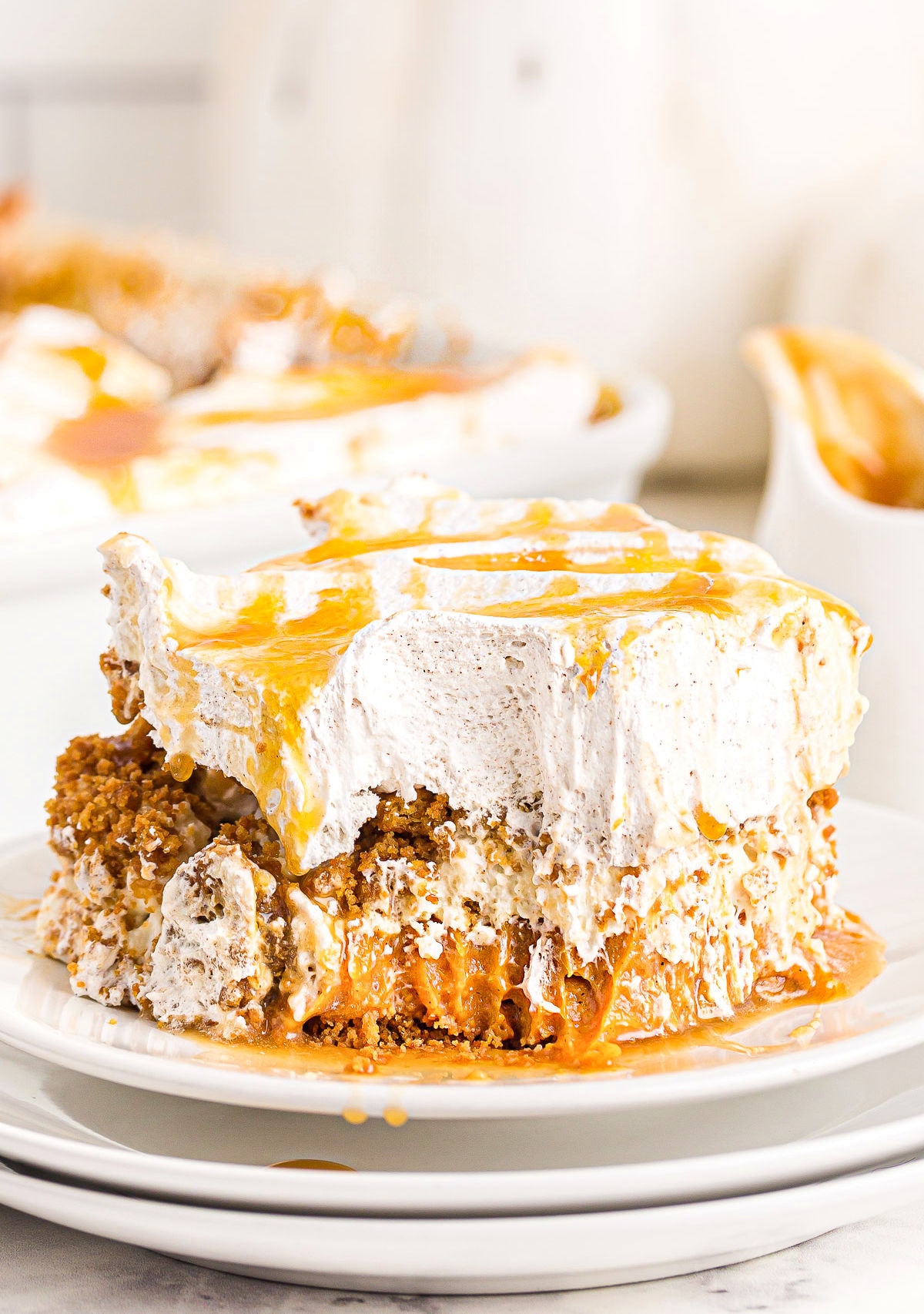 pumpkin dessert served on white plate with caramel sauce on top and baking dish in background