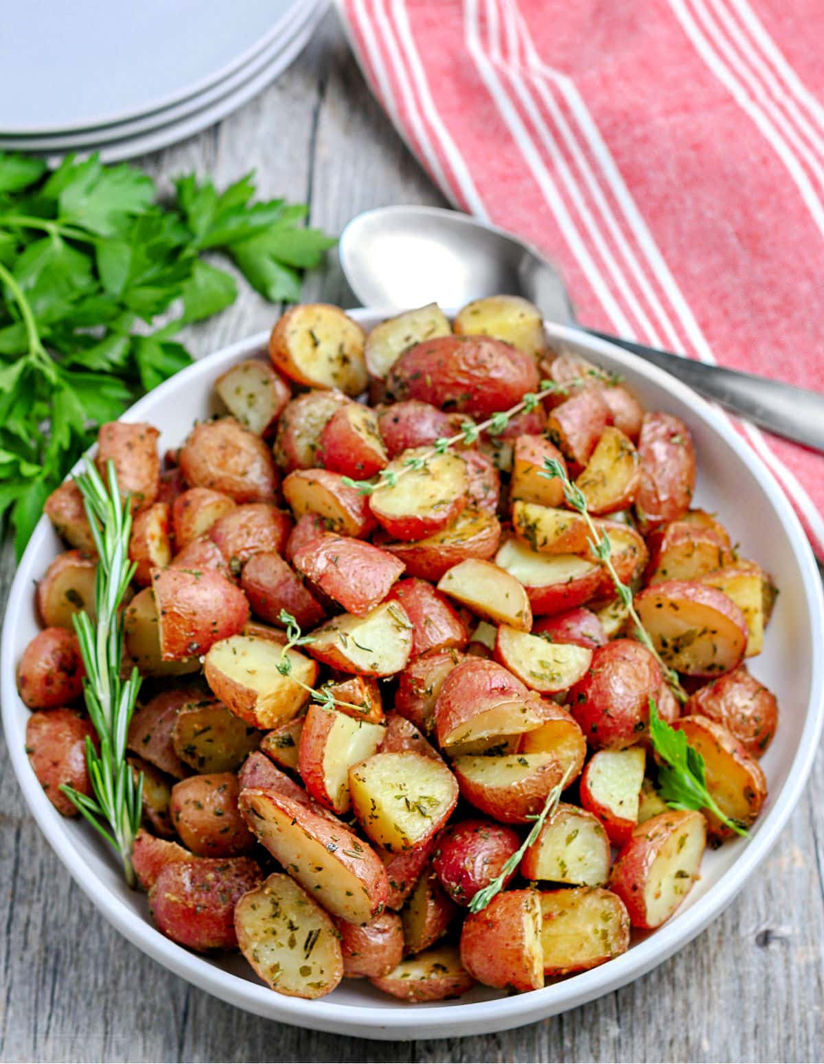 roasted red potatoes on white plate sitting on red and white striped towel