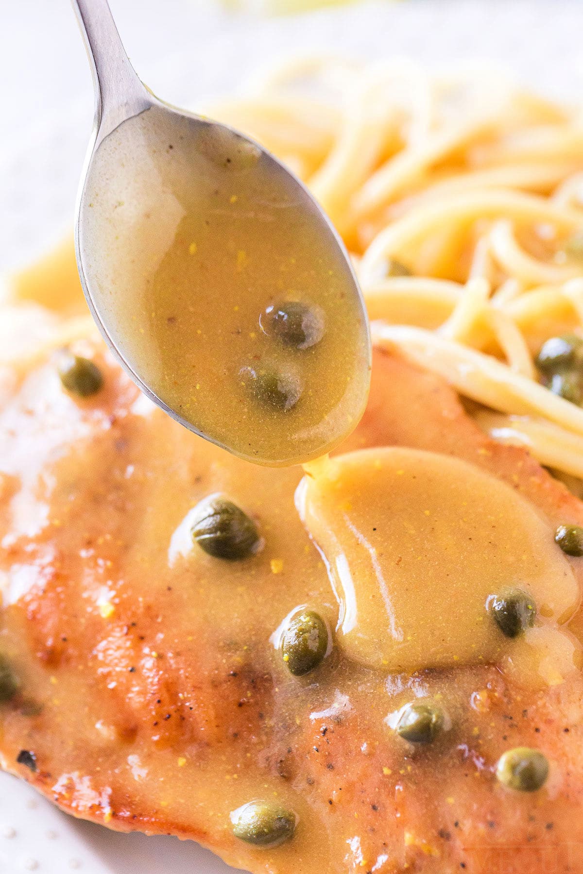 sauce being drizzled on chicken piccata