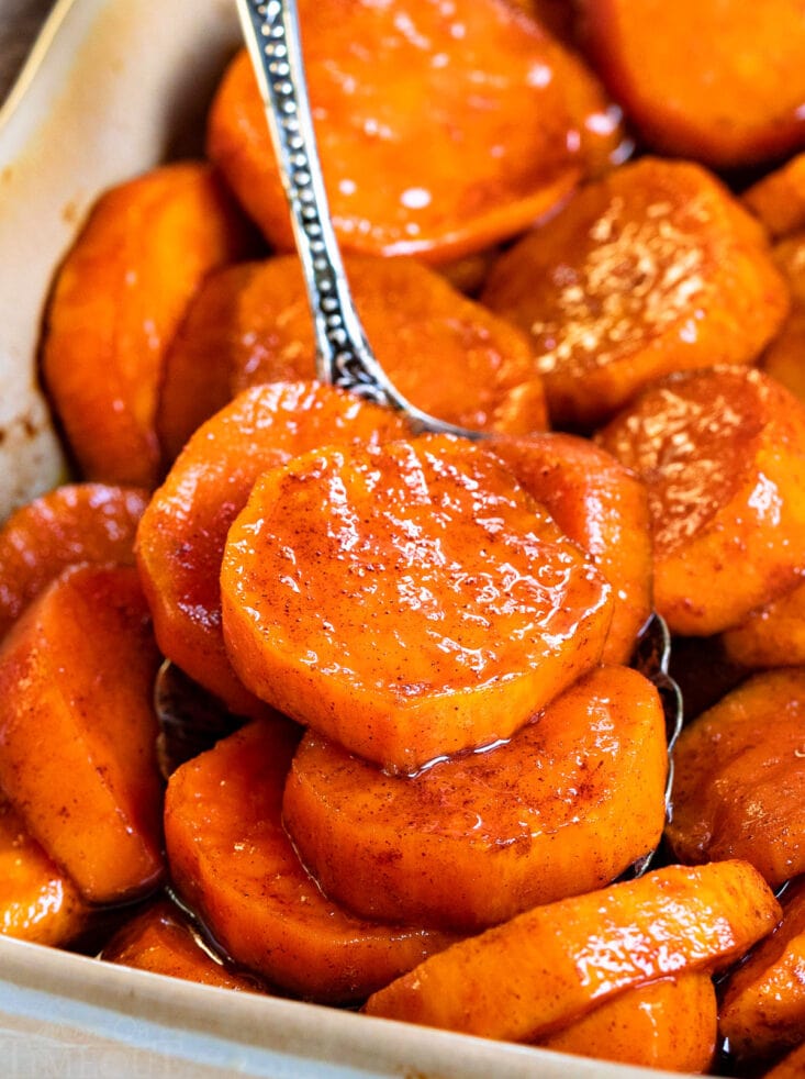 spoonful of candied sweet potatoes in beige baking dish