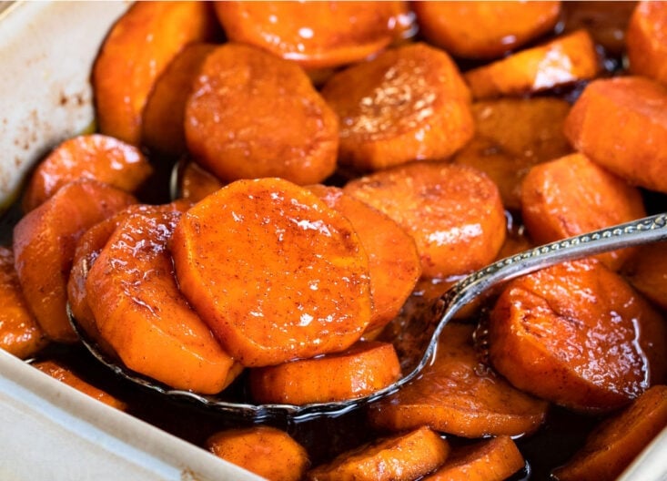 spoonful of candied sweet potatoes in beige baking dish