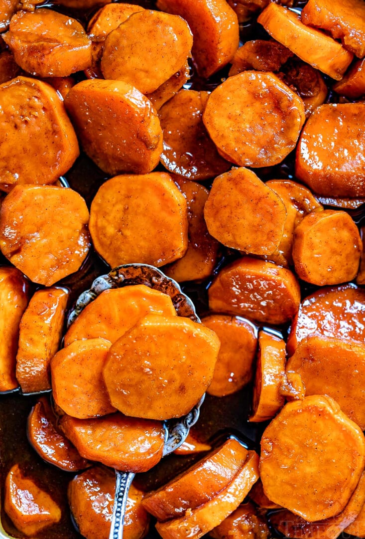 close up of candied yams in baking dish top down view title overlay at top antique spoon with a spoonful of yams at bottom of image