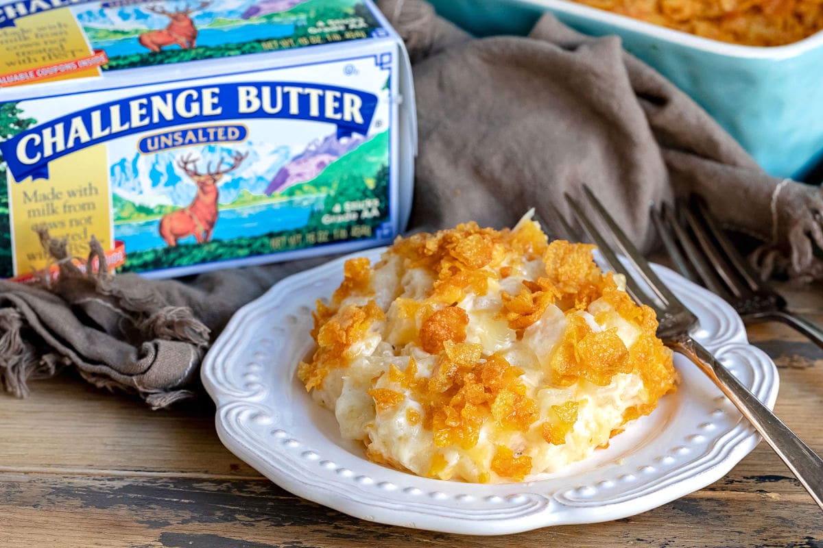 cheesy potatoes on white plate with challenge butter box behind it