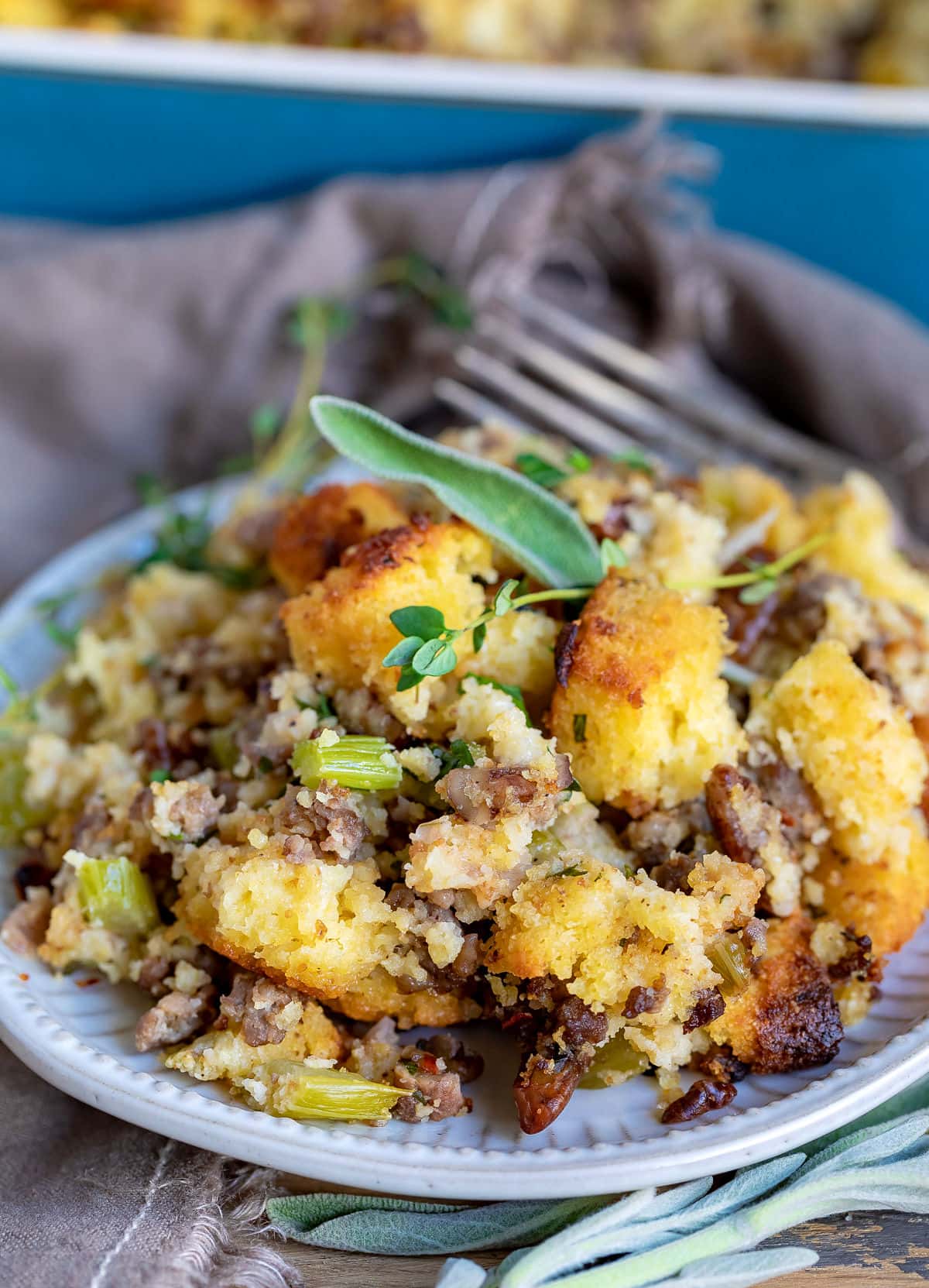 cornbread dressing on plate with fork and fresh herbs