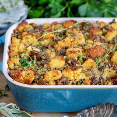 cornbread dressing in casserole dish with fresh herbs scattered on top