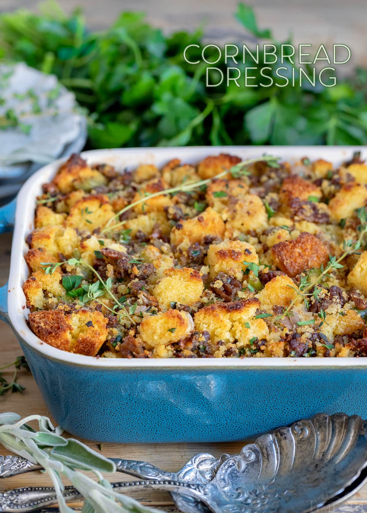 cornbread dressing in casserole dish with fresh herbs scattered on top and title overlay at top of image