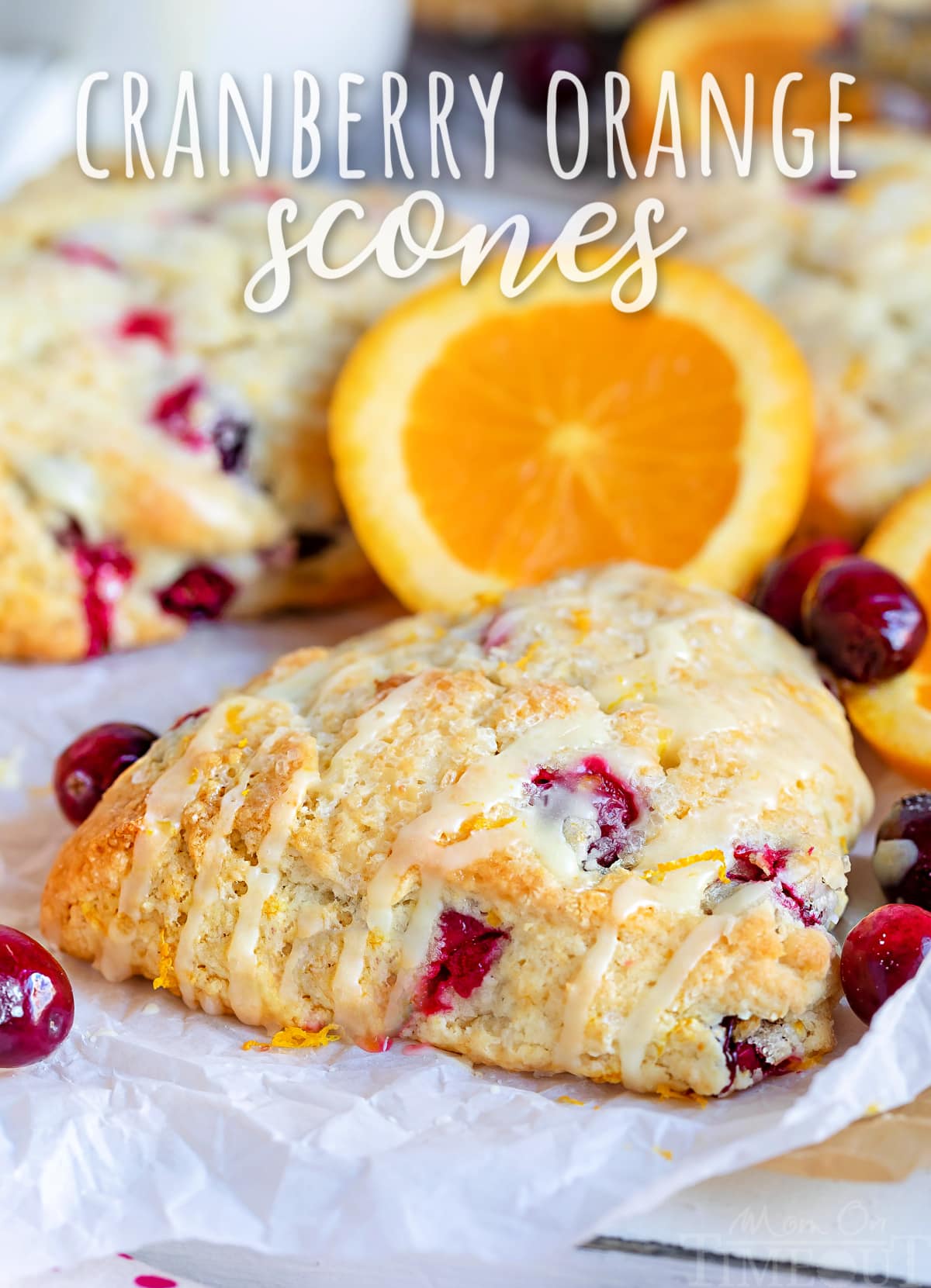 cranberry orange scone sitting on parchment paper with orange glaze drizzled on top with text overlay at top of image